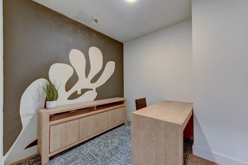 A room with a wooden bench and a wall art.