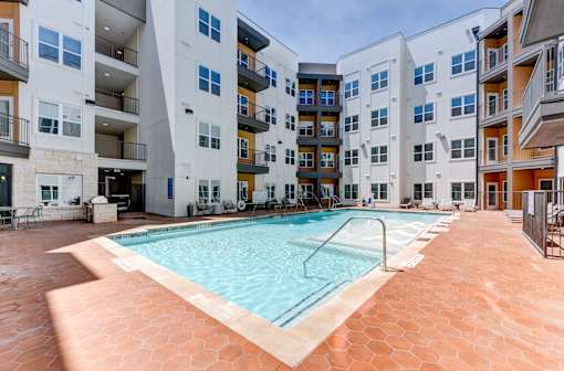 A large swimming pool in the middle of a courtyard surrounded by apartment buildings.