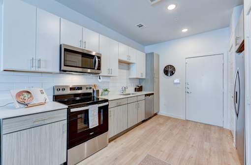 A modern kitchen with white cabinets and a wooden floor.