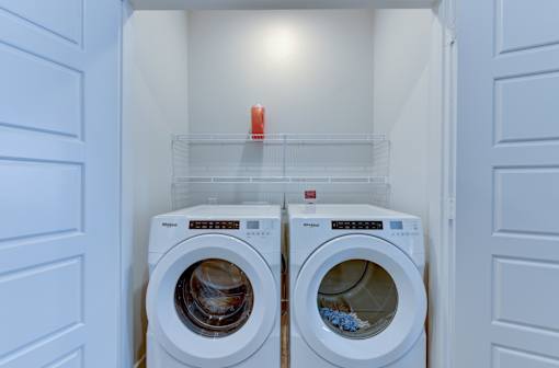 Two white front load washing machines in a laundry room.