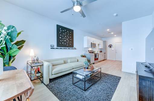A living room with a white couch, a coffee table, and a ceiling fan.