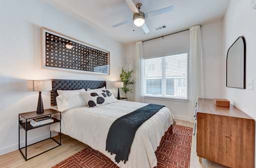 A bedroom with a bed, nightstand, and a ceiling fan.