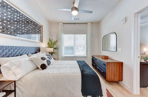 A bedroom with a bed, a dresser, and a mirror.