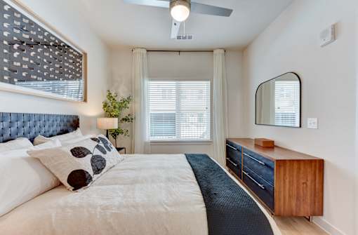 A bedroom with a bed, a dresser, and a mirror.
