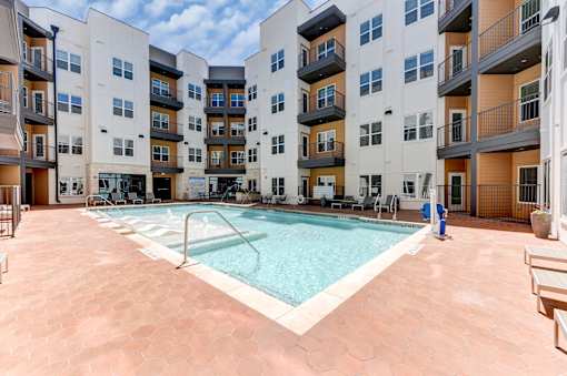A large swimming pool in the middle of a courtyard surrounded by apartment buildings.