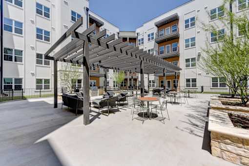 A patio with a table and chairs under a pergola.