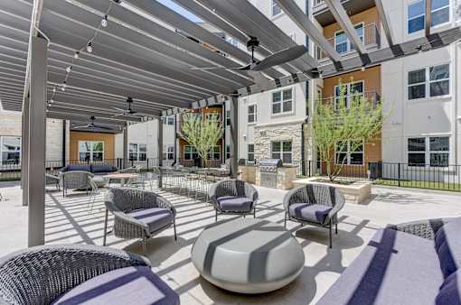 A patio with a white and grey wicker chair and a grey and white cushion.