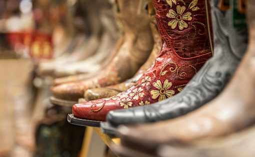 A row of cowboy boots with a red one in the front.