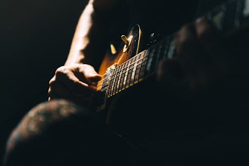 A person playing a guitar in a dimly lit room.