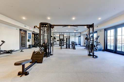 A spacious gym with a variety of equipment including treadmills, weights, and a bench.