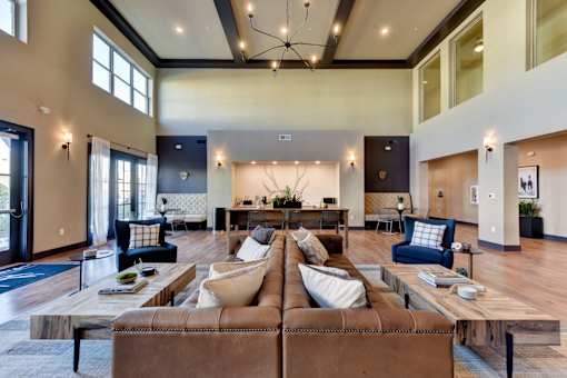 A large, modern living room with a brown leather sofa and a coffee table in the center.