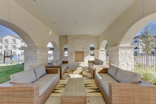 A patio with a woven couch and a table in the middle.