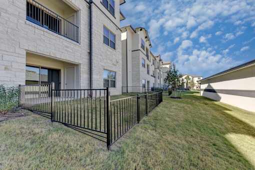 A black metal fence in front of a building with a grassy area.