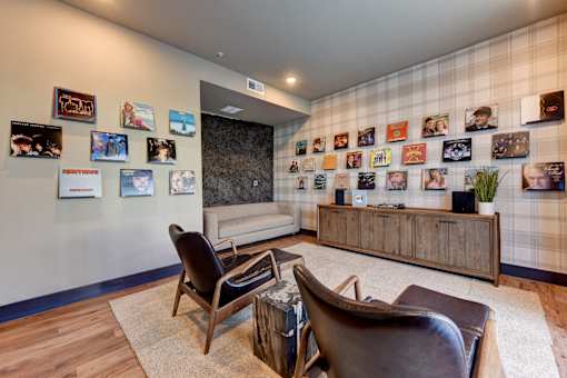 A living room with a couch, chairs, and pictures on the wall.