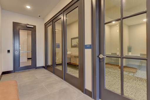 A hallway with a glass door and a brown bench.