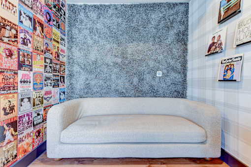 A white couch sits in front of a wall covered in posters.