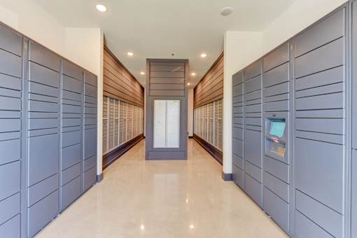 A hallway with a row of lockers on the side and a door at the end.