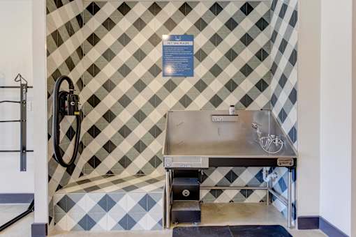 A bathroom with a black and white tiled wall and a sink.