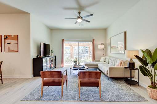 A living room with a couch, chairs, and a television.