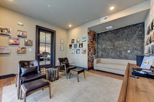 A living room with a couch, chairs, and pictures on the wall.