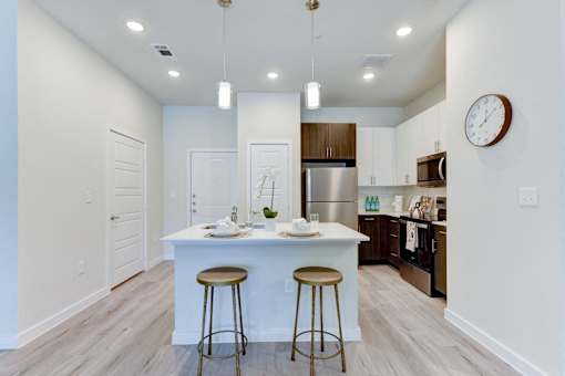 A kitchen with a white island and bar stools.