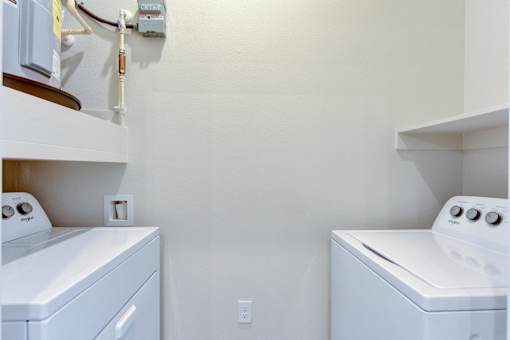 Two white washing machines in a small laundry room.