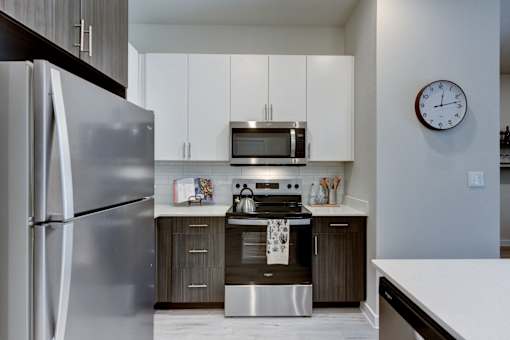 A modern kitchen with a stainless steel refrigerator and a microwave above the stove.