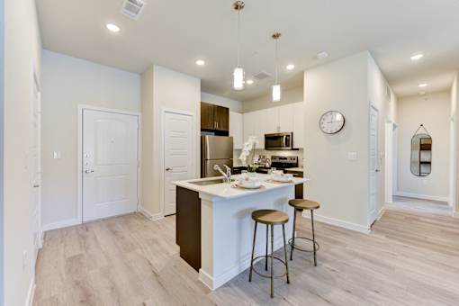 A kitchen with a bar stool and a clock on the wall.