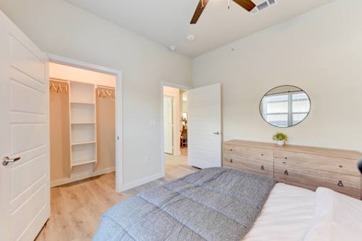 A bedroom with a bed, dresser, and a mirror on the wall.
