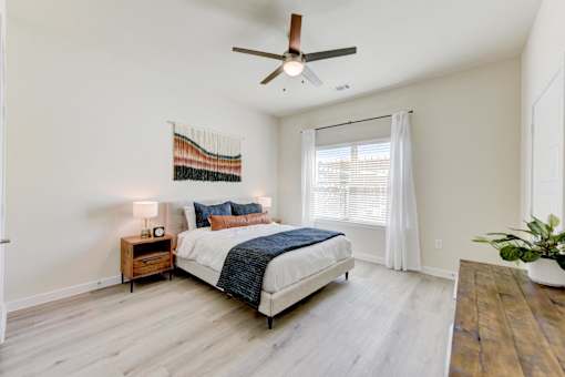 A bedroom with a bed, nightstand, and a plant.