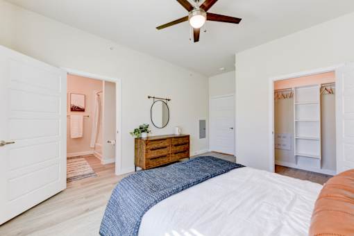 A bedroom with a bed, dresser, and a ceiling fan.