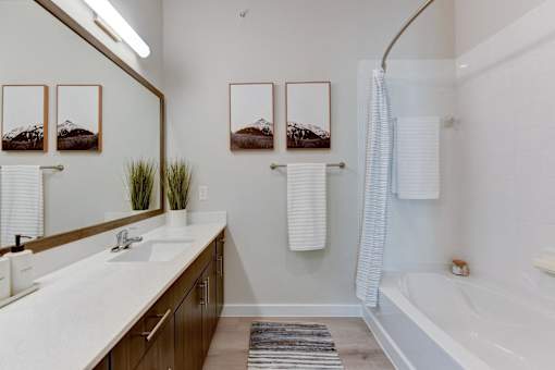 A bathroom with a white tub, sink, and mirror.