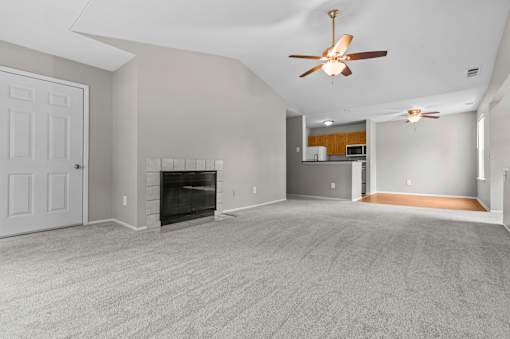 A spacious living room with a fireplace and a ceiling fan.