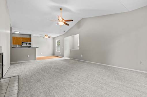 A spacious room with a ceiling fan and carpeted floor.