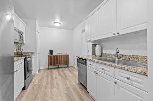 Galley kitchen with granite countertops and white cabinets at Regents Club of Troy Apartments, Troy, MI 48084