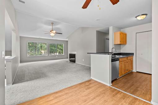 A spacious kitchen and living room with a ceiling fan and a large window.