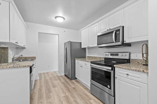 Modern kitchen with white cabinets and granite countertops at Regents Club of Troy Apartments, Troy, 48084
