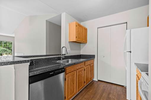 A kitchen with a black counter top and white appliances.