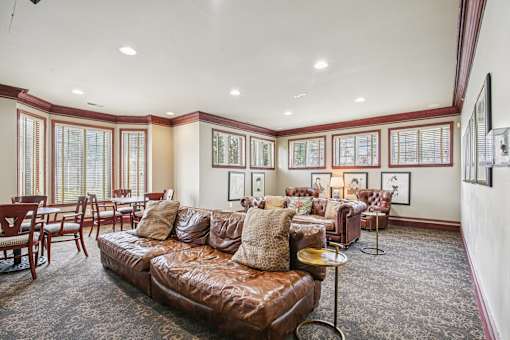 A living room with a brown leather couch and a patterned carpet.
