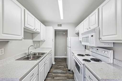 A white kitchen with a sink and stove.