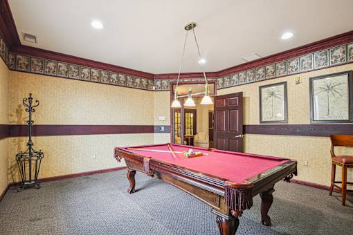 A pool table in a room with a chair and a wall with pictures.