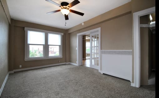 Carpeted bedroom with ceiling fan and double doors with glass panes.