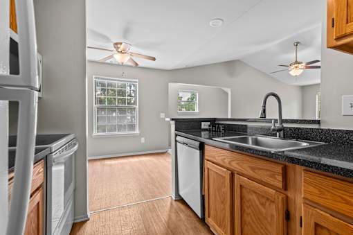 A modern kitchen with a black countertop and wooden cabinets.