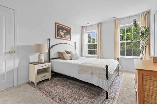Bedroom with metal bed frame and white bedding at Regents Club of Troy Apartments, Troy, Michigan