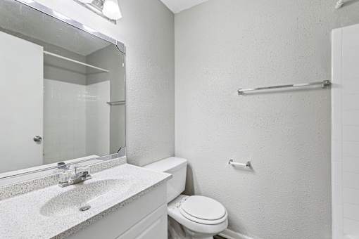 A white bathroom with a toilet, sink, and mirror.