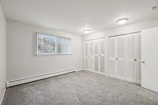 A room with white walls and a window with blinds.