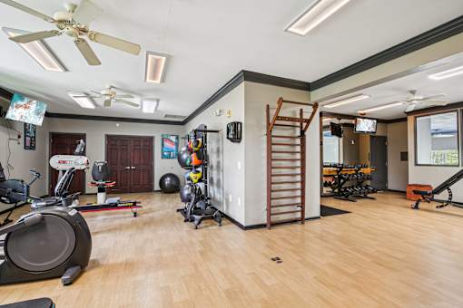 A spacious home gym with wooden floors and a variety of exercise equipment.