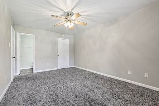 A room with a ceiling fan and carpeted floor.