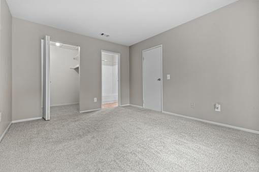 A large, empty room with a carpeted floor and two doors.