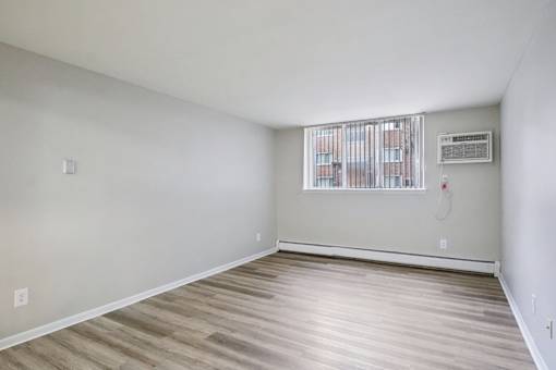 A room with wooden flooring and a window with bars on it.